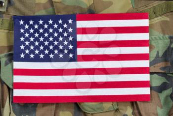 Top view angled shot of United States flag with military uniform background.  