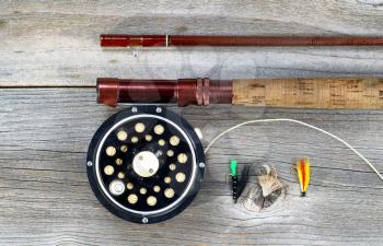 Antique fly fishing reel and rod on rustic wood. Layout in horizontal format.