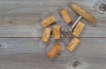 Several used wine corks and opener on rustic wooden boards. Top view angled shot in horizontal format with copy space. 