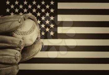vintage concept of worn leather mitt and used baseball with United States of America flag in background. 