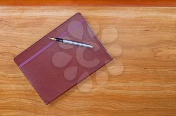 Executive notepad with pen on cherry wood desktop with plenty of copy space. 