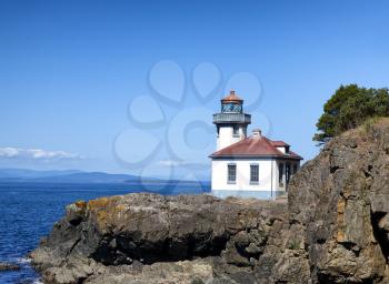 Lighthouse on the Puget Sound of Washington state during nice day with blue sky and clouds. 