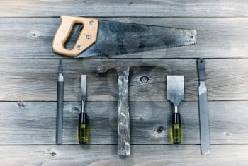 Vintage concept of used tools on rustic wooden boards consisting of hammer, metal files, hand saw, and chisels. 