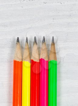 Close up of colorful sharpen pencil tips on white desktop. Layout in vertical format.
