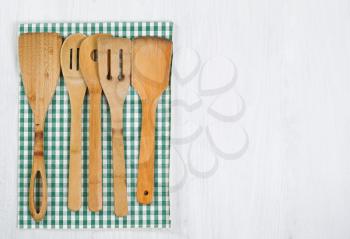 Wooden spatula, spoons with striped cloth napkin on white wood. Horizontal layout with plenty of copy space.
