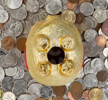 Close up of upside down piggy bank, focus on complete belly, with loose coins underneath. Concept of financial hard times. 

