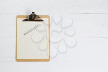 Clipboard with paper and pen on white desktop.