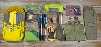High angled view of organized hiking gear placed on rustic wooden boards in rectangle format. 