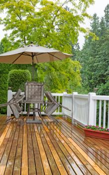 Vertical photo of outdoor patio furniture put away due to poor weather. Heavy rain on cedar wood deck. 