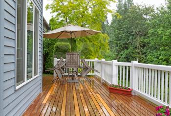 Horizontal photo of outdoor patio furniture put away due to poor weather. Photo taken during heavy rain on cedar wood deck. 