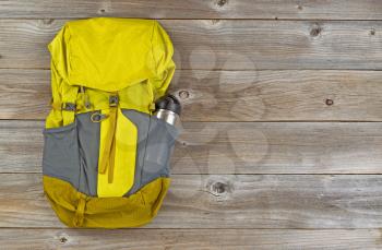Weather proof backpack with metal canteen on rustic wooden boards. 