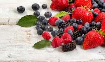 Close up of fresh berries on rustic white wooden table. 