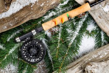 Fishing gear with evergreen branches and old driftwood covered in snow.
