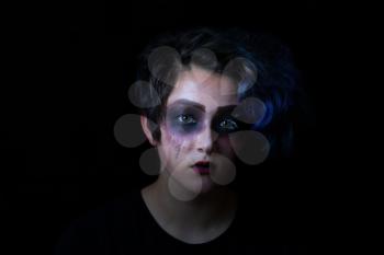 Teen girl in scary makeup on black background. 