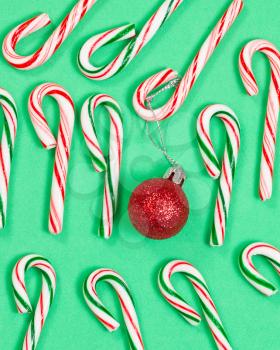 Collection of candy canes with red ornament on green background. 