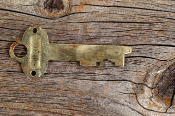 Old brass key on rustic wood. Close up view in horizontal format.