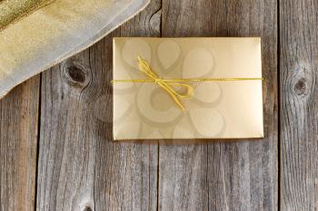 Golden color wrapped gift box and ribbon on rustic wood. Holiday concept of giving. 