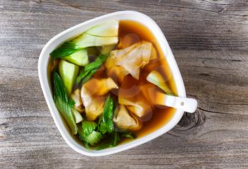 Top view Chinese wanton soup with bok choy on rustic wood. 