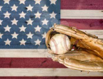Close up of baseball mitt and ball with painted boards of USA flag.  