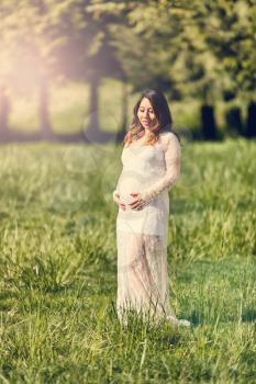 Expecting mom in open grassy field. Haze light effect applied to image.    