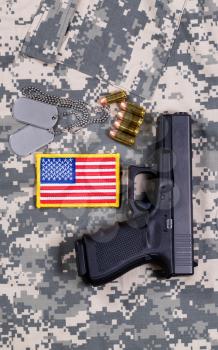 USA flag patch, ID tags, pistol, bullets on military battle dress uniform. 