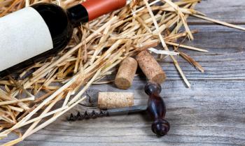 Close up of vintage wine corkscrew with bottle of wine on straw in background. Selective focus on corkscrew. 