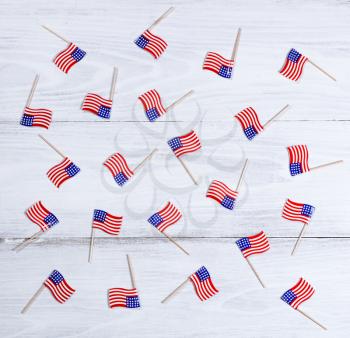 Small USA flags scattered on rustic white wooden boards. Fourth of July holiday concept for United States of America.  