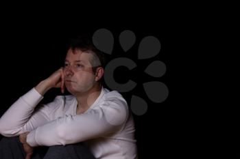 Side view of depressed mature man in thought.  Dark background with copy space available. 