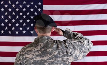 Veteran soldier, back to camera, saluting USA flag. 