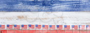 Small USA flags on bottom of red, white and blue rustic boards. Fourth of July holiday concept for United States of America.  