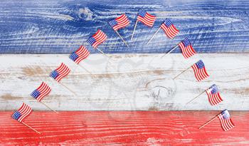Small USA flags forming arch formation on red, white and blue rustic boards. Fourth of July holiday concept for United States of America.  