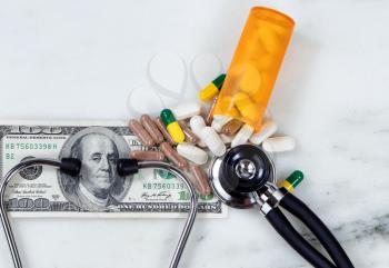 Medical costs concept with pills, bottle, stethoscope, and paper currency.    