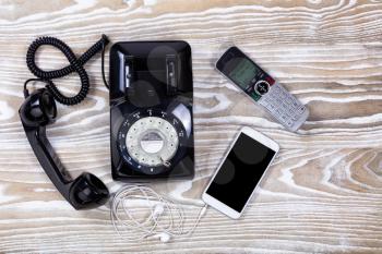 Overhead view of old rotary phone with modern wireless home and cellphone 