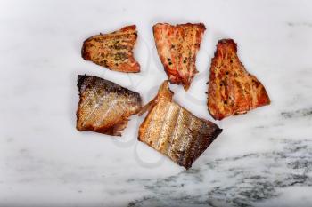 Overhead view of freshly smoked red salmon fillets on natural marble stone counter. 