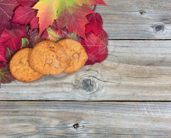 Fresh whole caramel apple cookies and autumn leaves on rustic wood