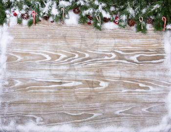 Rustic white wooden background for Christmas concept with snow covered fir branches, candy canes and pine cones. Overhead view with copy space.

