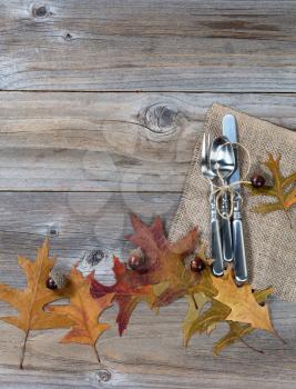 Autumn dinner place setting for Thanksgiving holiday in vertical layout on rustic wooden boards. 