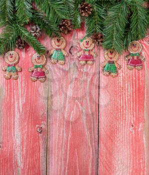 Christmas holiday gingerbread cookies and evergreen branches on rustic red wood. Vertical format.     