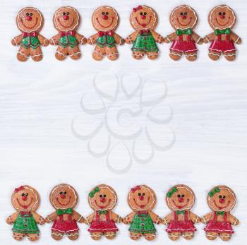 Christmas holiday gingerbread cookies forming top and bottom border on white wood.   