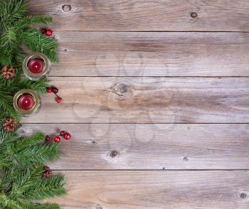Seasonal fir evergreen branches and candles on rustic wooden boards for the holidays. Top view.