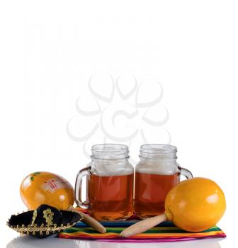 Cinco de Mayo concept with freshly poured beer, maracas, sombrero and placemat serapes on glass table isolated on white.