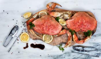 Overhead view of cooked crab on wooden server with utensils and spices 