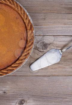 Overhead view of Pumpkin pie and spatula server on rustic table in vertical format 