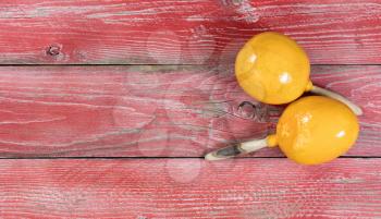 Flat view of yellow maracas on rustic red wooden boards for Cinco de Mayo concept. 
