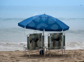 Two empty beach chairs with umbrellas on the Pacific Ocean 