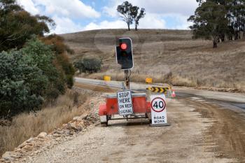 Mobile traffic light and signs on rural road for construction repairs. 
