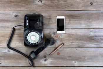 Overhead view of antique phone with modern smartphone on rustic wood 