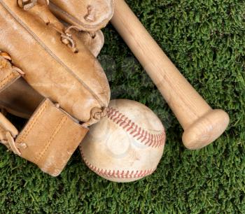 Flat view of old baseball mitt, ball and bat on grass