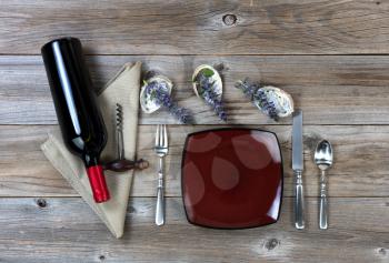 Dinner setting with nature decorations and red wine bottle on rustic wooden table in flat lay view