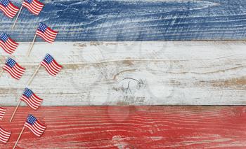 Flay lay view of USA mini flags on rustic wooden boards painted in red, white and blues colors. 